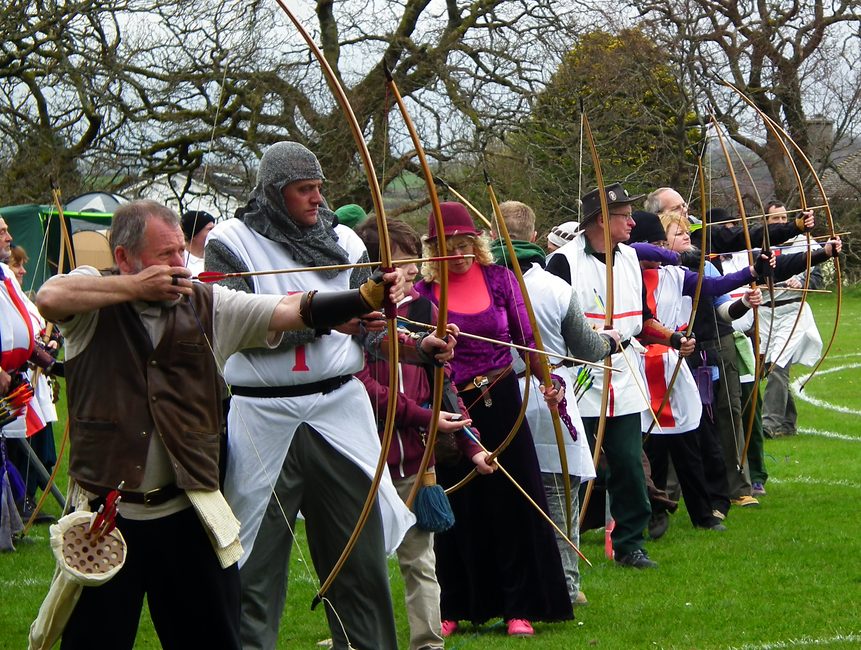 Traditional archers in costume standing at full draw