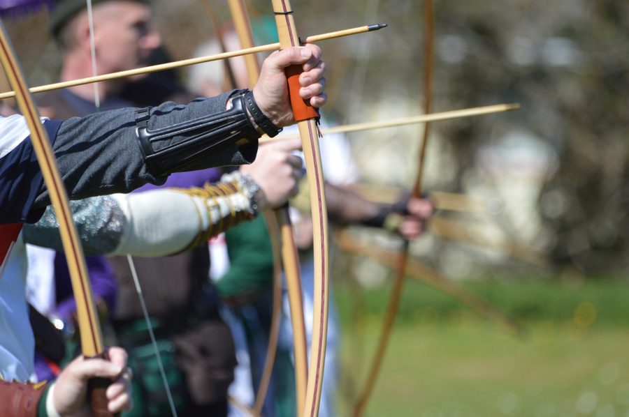 Close view of archers holding longbows on the shooting line