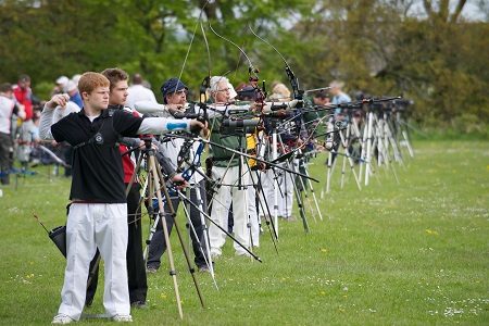 Archers with recurve and compound bows on an outdoor competition line